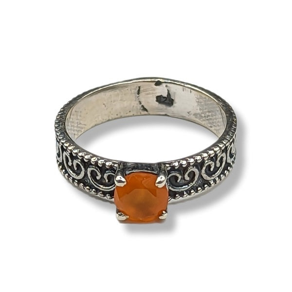 Silver ring with an orange gemstone on a white background