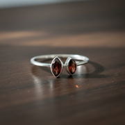 Silver ring with two red gemstones on a wooden surface