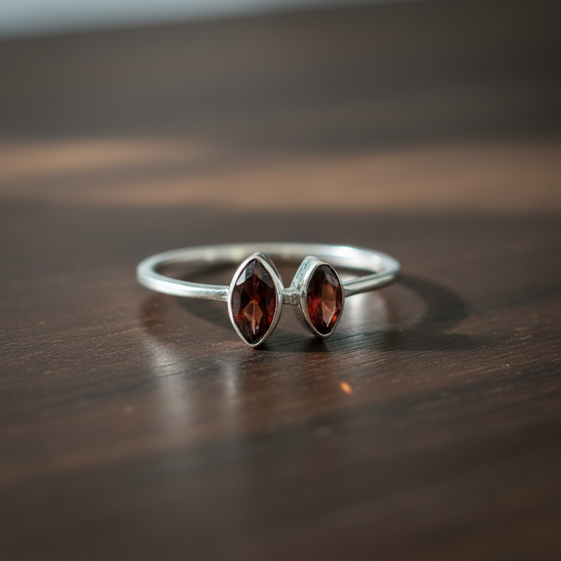 Silver ring with two red gemstones on a wooden surface