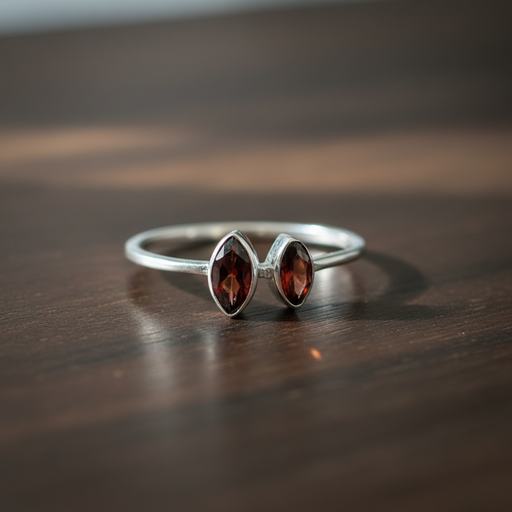 Silver ring with two red gemstones on a wooden surface