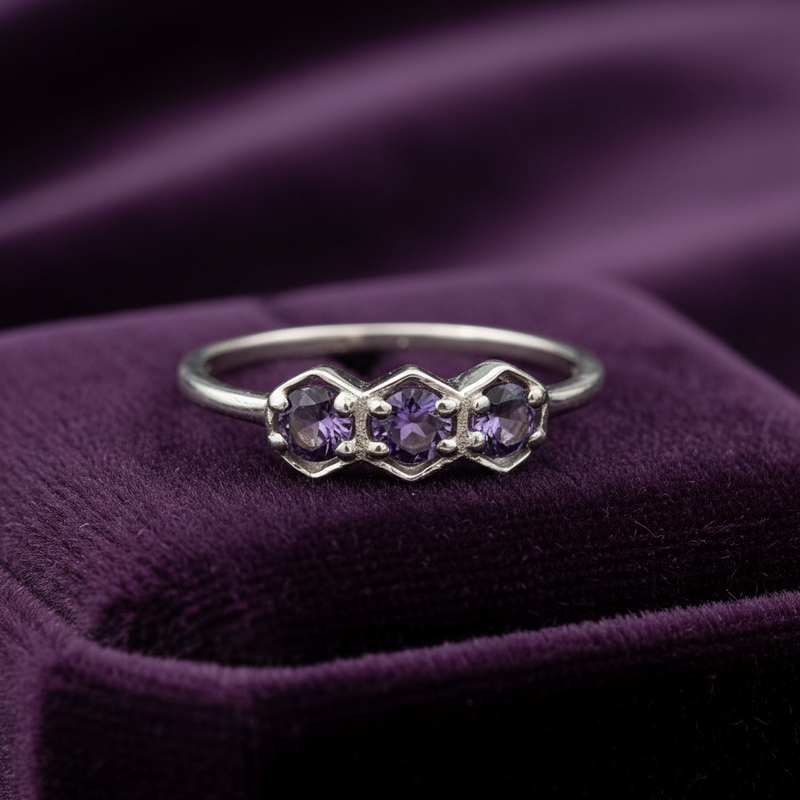Silver ring with purple gemstones on a purple fabric background