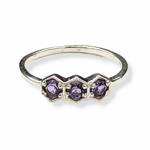 Silver ring with three purple gemstones on a white background