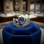 Silver ring with blue gemstone on a blue pillow