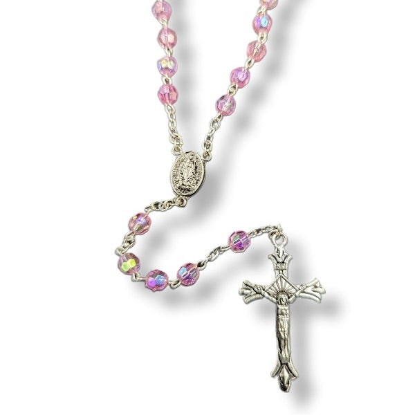 Rosary with pink beads and a silver cross on a white background
