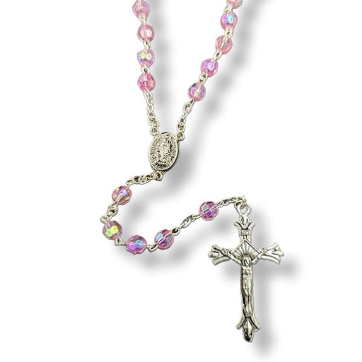 Rosary with pink beads and a silver cross on a white background