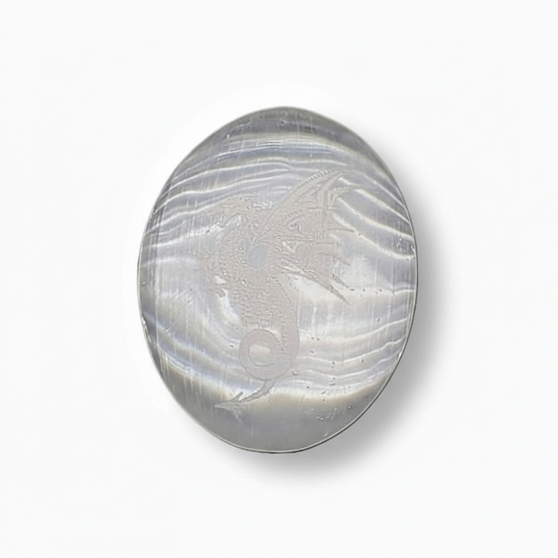 Selenite palm stone  with a etched dragon set against a plain white background.