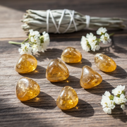 Tangerine aura tumbled crystals on a table with sage and white flowers.