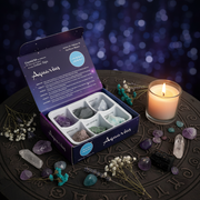 Aquarius crystal kit with crystals and a candle on an astrological symbol mat.