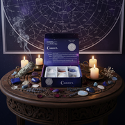 Open box labeled 'Cancer' with crystals on a wooden table in front of a star map.