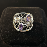Silver ring with purple gemstones on a black background