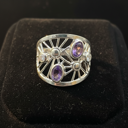 Silver ring with purple gemstones on a black background