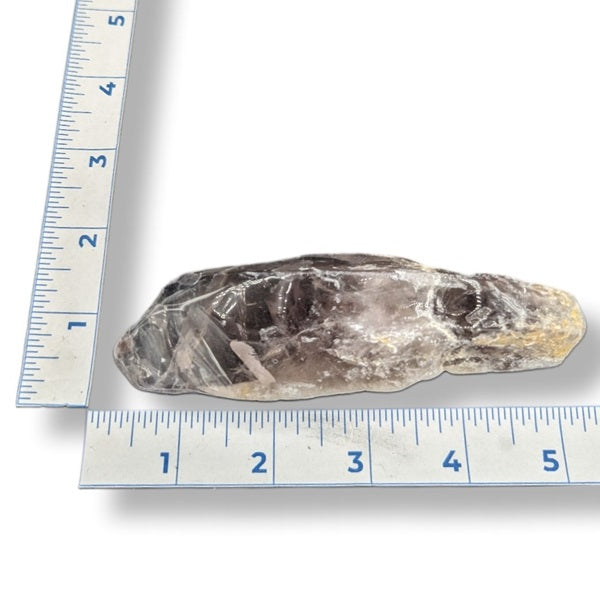 Amethyst crystal next to a ruler on white background