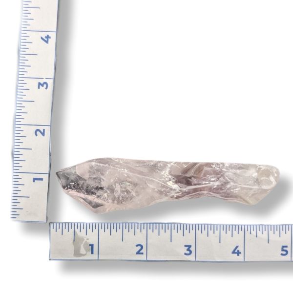 A rough, translucent pale pink crystal or gemstone shown on a white background with blue measurement rulers along the left and bottom edges for size reference.