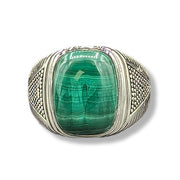 Ring with a green gemstone and silver band on a white background
