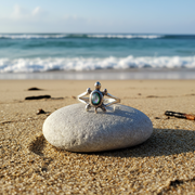 Silver ring with a green stone on a white stone at the beach