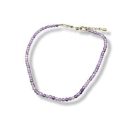 Purple beaded anklet with a gold clasp on a white background