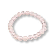 A beaded stretch bracelet made of translucent light pink round beads, shown on a clean white background with a soft drop shadow.