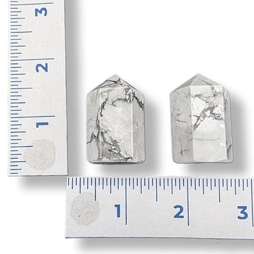 Two Howlite towers next to a ruler on a white background