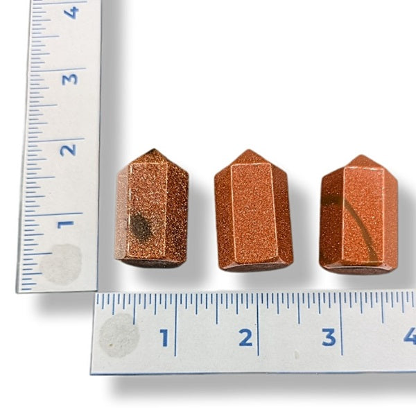 Three Goldstone Points next to a ruler on a white background