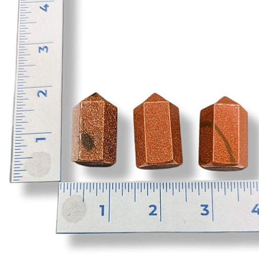 Three Goldstone Points next to a ruler on a white background