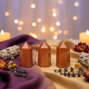 Three Goldstone Points in a spiritual setting surround by dried flowers, sage and candles in the background