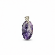 Purple stone pendant  next to a ruler for scale on a white background