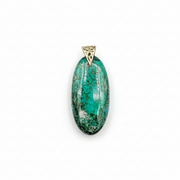 Green stone pendant next to a ruler on a white background