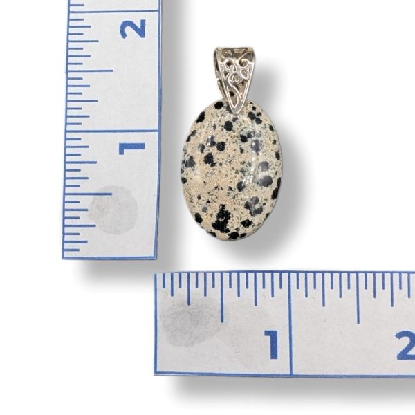 Pendant with speckled stone and silver setting next to a ruler for scale
