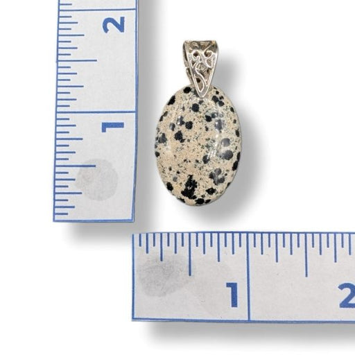 Pendant with speckled stone and silver setting next to a ruler for scale