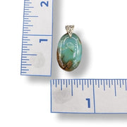 Chrysoprase pendant with gold chain next to a ruler for size reference on a white background