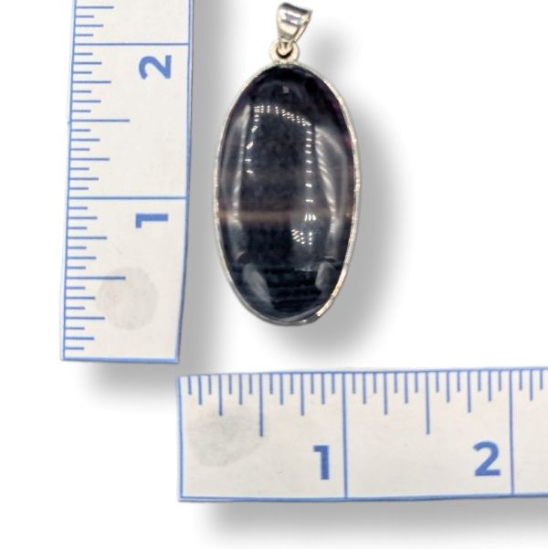 Oval-shaped pendant with sterling silver  on a white background with ruler for scale