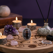 Wiccan altar setup with candles, crystals, and a pendant on a wooden board.