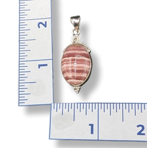 Pink and silver pendant on a ruler for scale