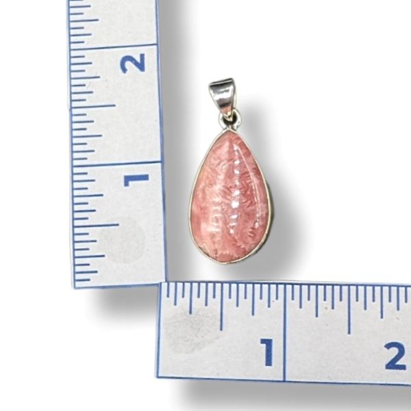 Pink teardrop pendant on a white background with a ruler for scale.