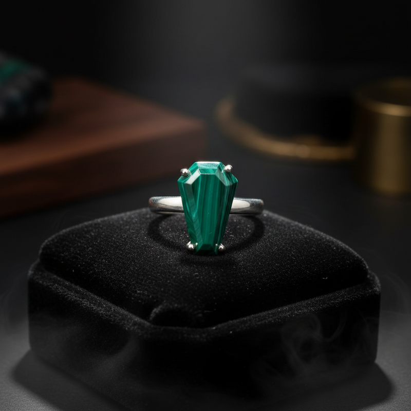A sterling silver malachite ring resting on a black pillow