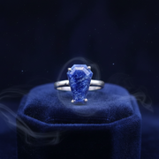 Blue gemstone ring on a blue cushion with a dark background