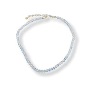 A delicate beaded anklet with light blue faceted beads and a gold-tone clasp, displayed on a clean white background.