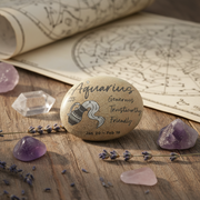 Decorative stone with Aquarius zodiac sign on a wooden surface with crystals and lavender.