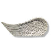 A white angel wing memorial plaque with engraved black text reading 'May you find comfort in the arms of an angel' on a plain white background.
