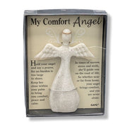 A packaged comfort angel figurine with a printed message card behind it. The product includes a small white angel statue and a beige insert card titled "My Comfort Angel" with comforting text, shown in a clear-front gift box.