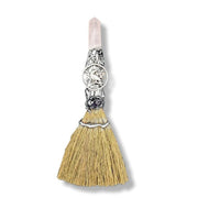 Decorative broom with a silver handle and rose quartz crystal on a white background