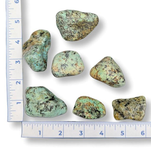 Turquoise stones with a ruler on a white background