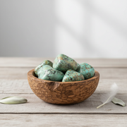 Wooden bowl filled with turquoise stones on a light wooden surface