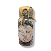 Glass jar labeled 'Road Opener Spell Jar' with a string and yellow wax on a white background