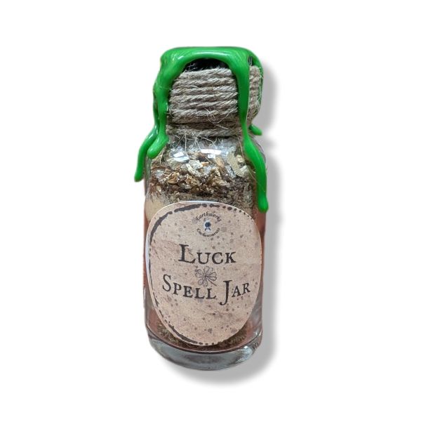 Small glass jar labeled 'Luck Spell Jar' with green wax on a white background