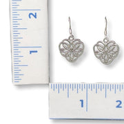 Silver heart-shaped earrings next to a ruler for scale on a white background