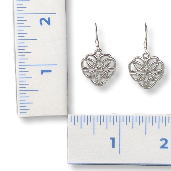 Silver heart-shaped earrings next to a ruler for scale on a white background