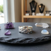 Silver ring with braided design on a piece of slate with other crystals