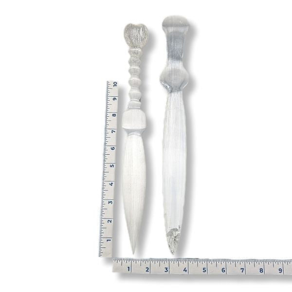 Two decorative selenite knives with a ruler for scale on a white background