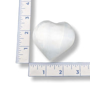 Heart-shaped selenite next to a ruler on a white background